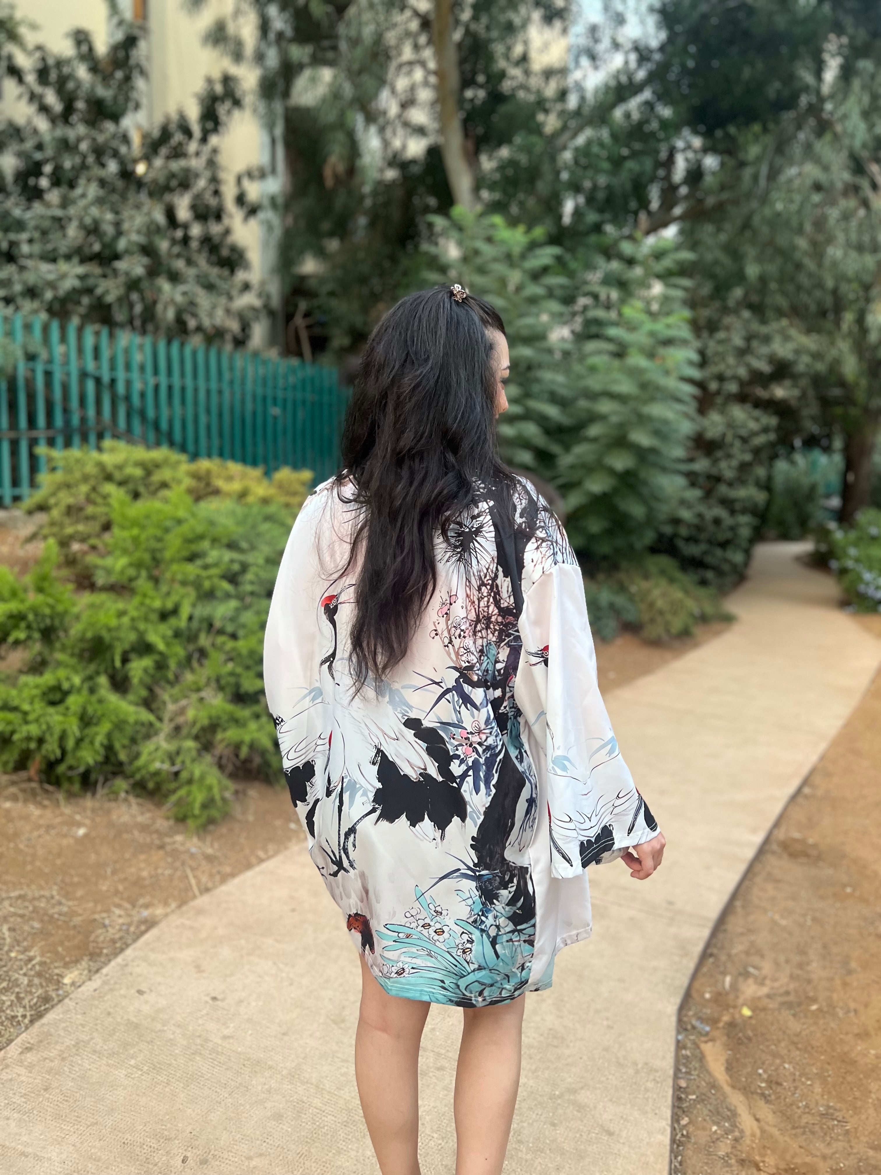 Woman in a floral kimono walking on a path in a garden