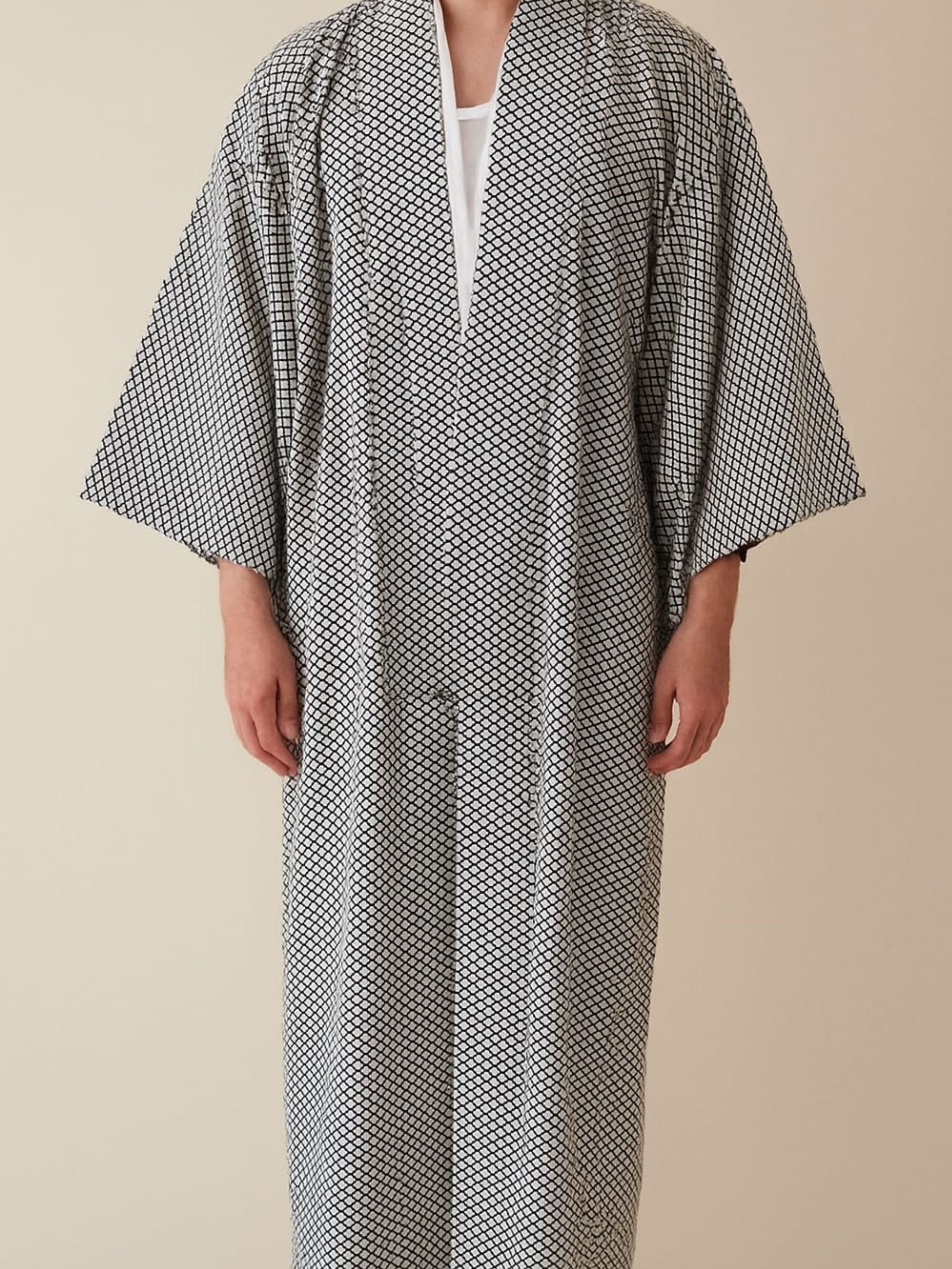 Person wearing a long, black and white patterned kimono with a neutral background