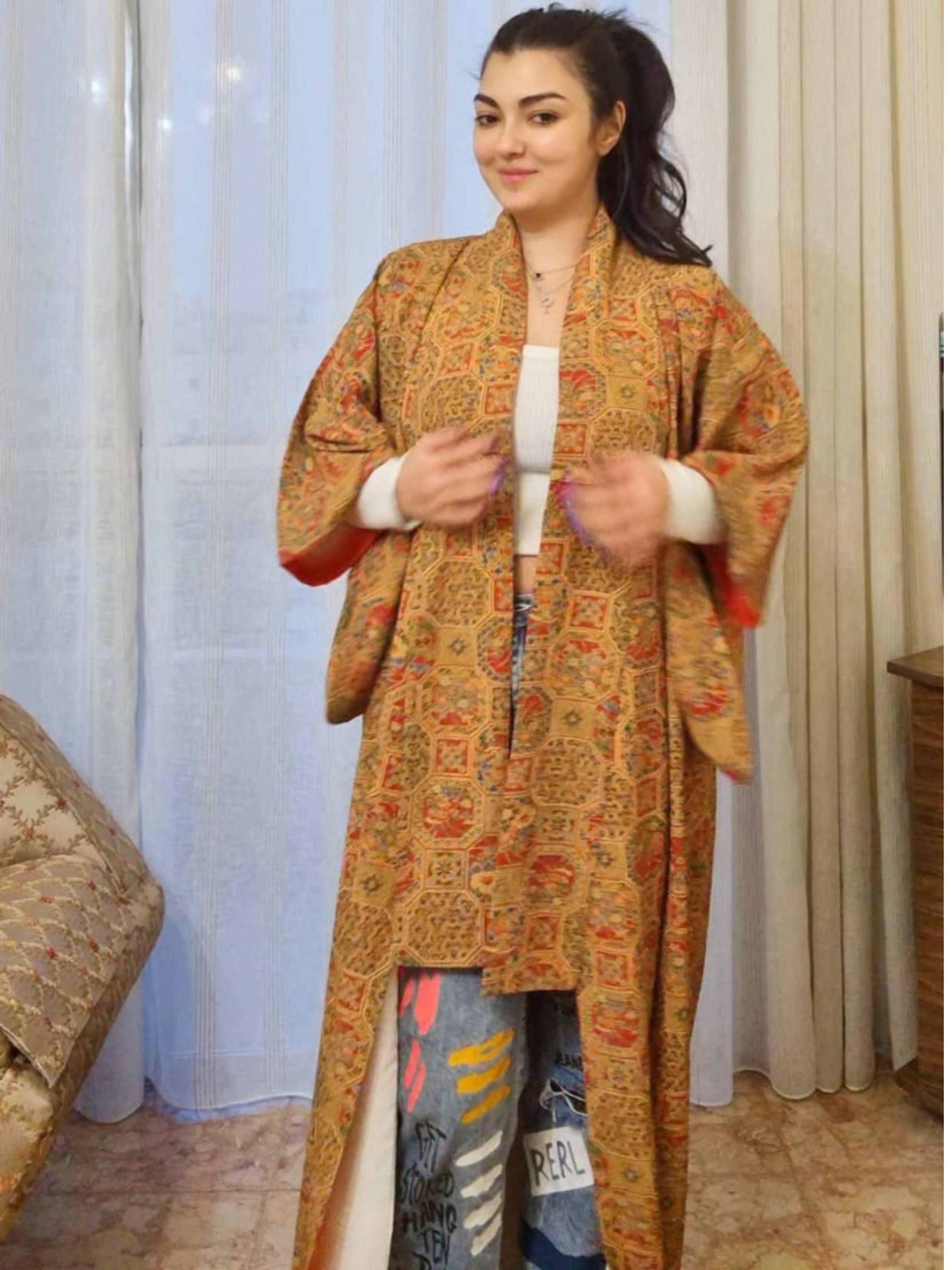 Woman wearing Japanese kimono golden patterned in a room with curtains 