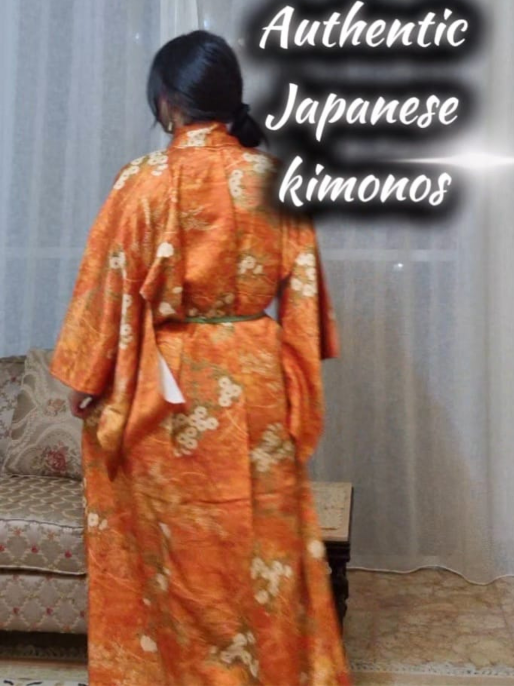 Person wearing an orange kimono with floral patterns in a room.