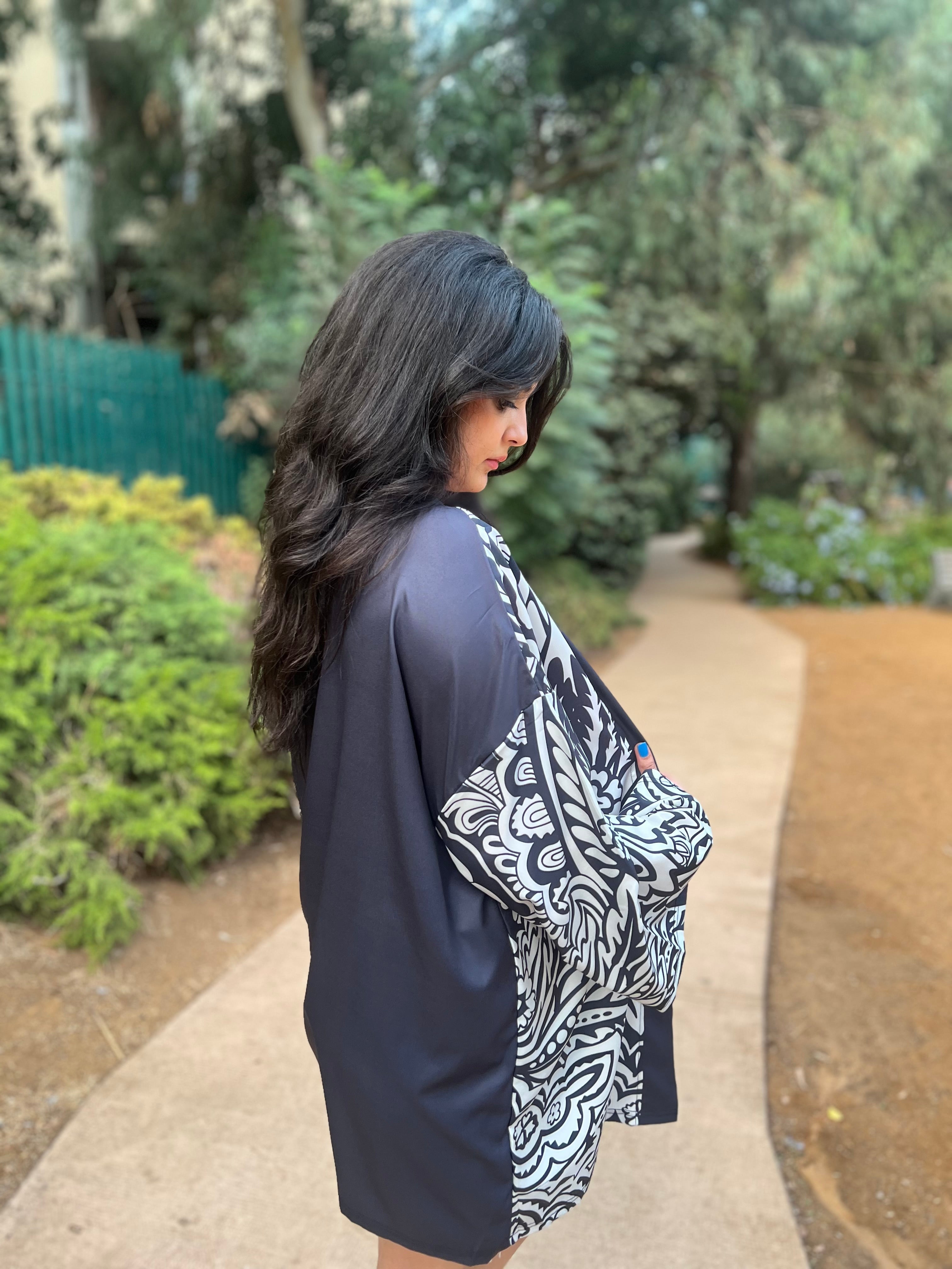 Woman wearing a dark robe with white patterns in a garden setting